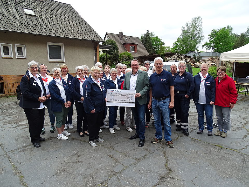 im Beisein des Vorstandes und der Aktiven des DRK-Ortsvereins überreicht Bürgermeister Oelmann den Scheck der Gemeinde Winsen (Aller) an Teamleiterin Kleiderkammer Frau de Schipper und Frau Meyer